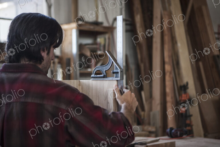 Caucasian man factory worker checking square measurements on a wooden part in a…