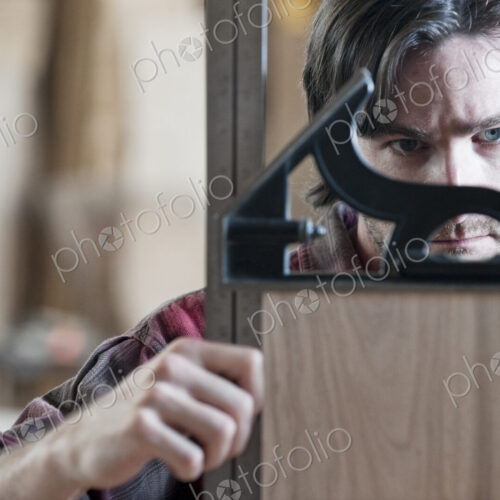 Caucasian man factory worker checking square measurements on a wooden part in a…
