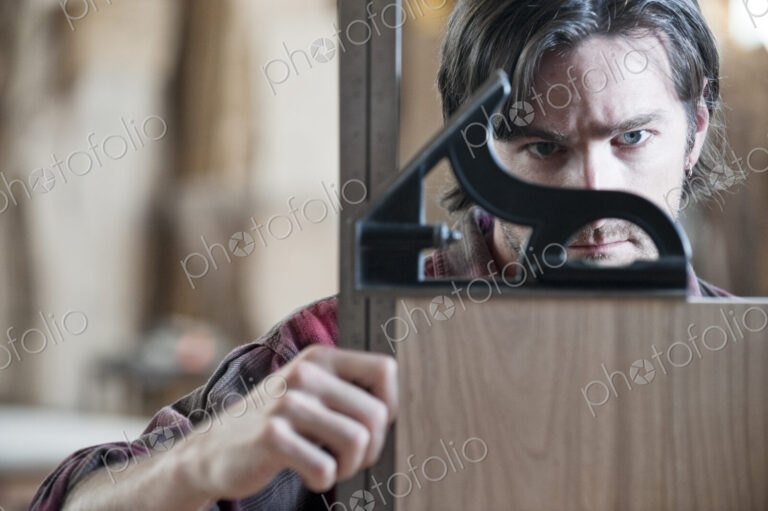 Caucasian man factory worker checking square measurements on a wooden part in a…