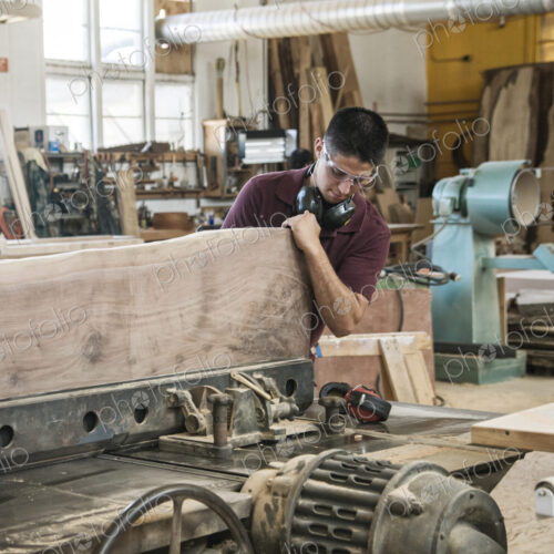 Caucasian man factory worker cutting a large wooden slab in a woodworking factory.