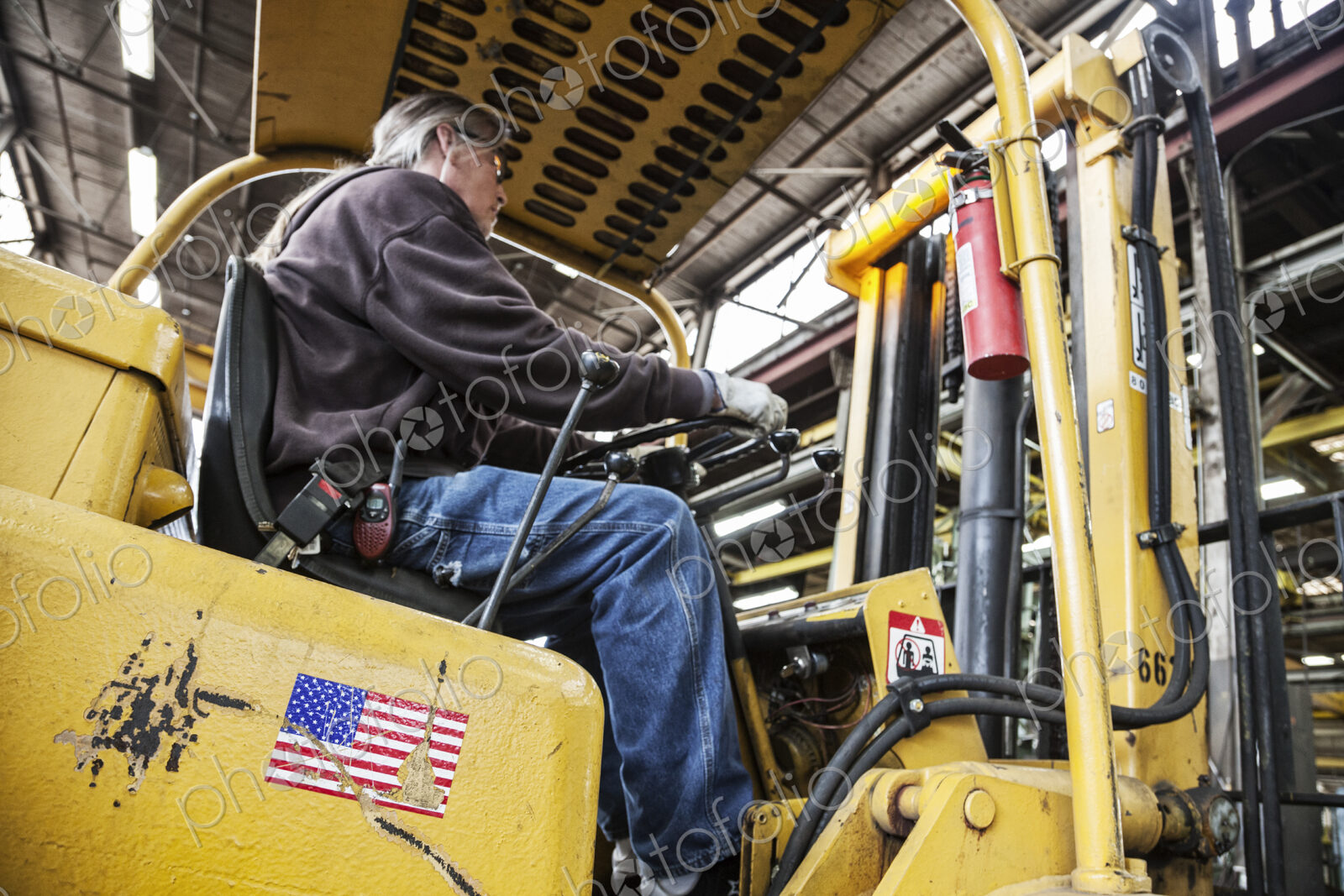 Caucasian man factory worker driving a fork lift in a sheet metal factory.