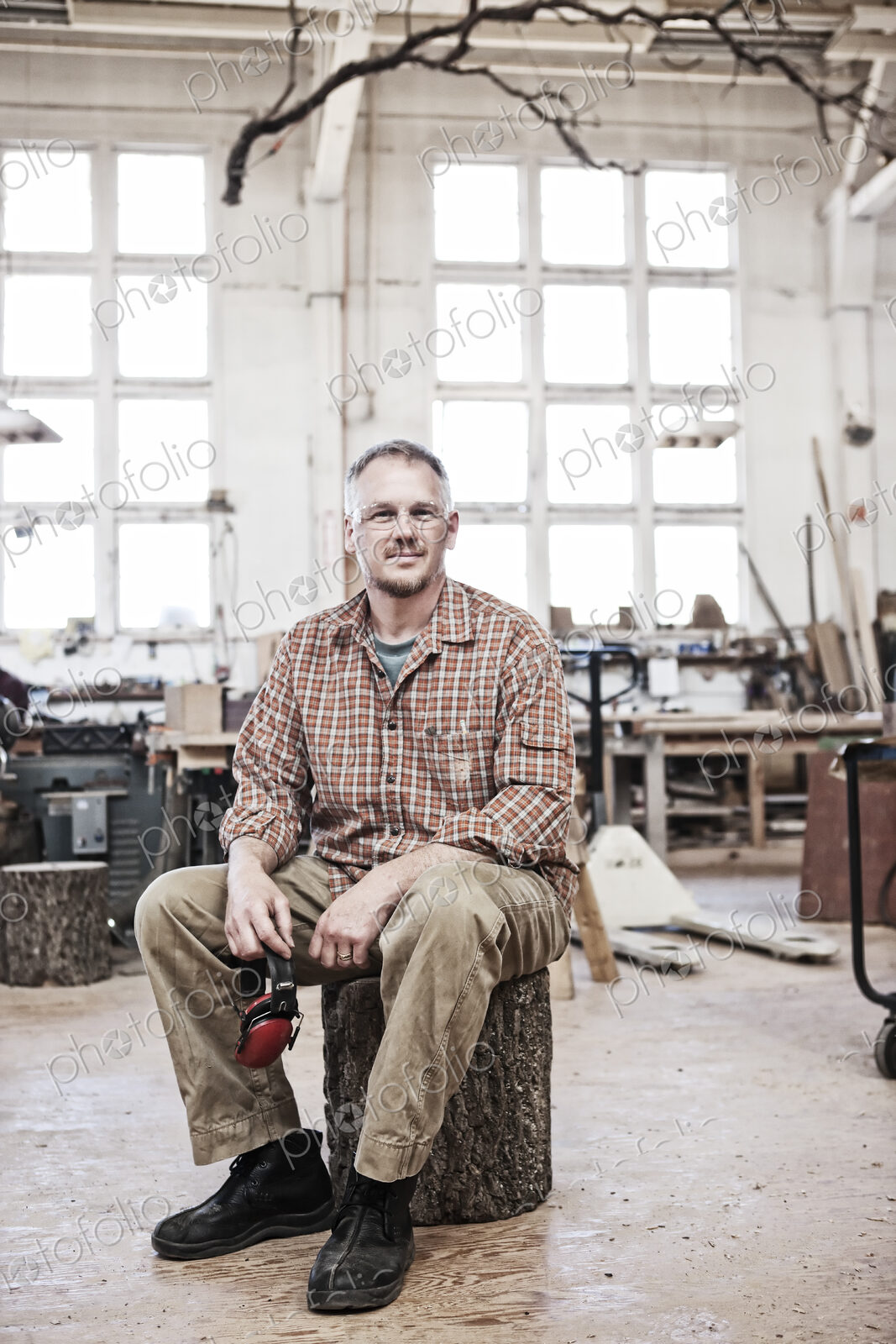 Caucasian man factory worker sitting on a stool in a woodworking factory.