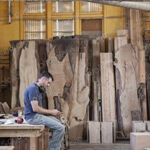 Caucasian man factory worker taking a break checking phone messages in a woodworking…