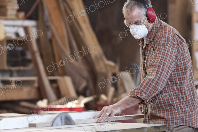 Caucasian man factory worker wearing hearing protection and a nose dust mask while…