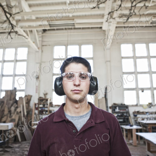 Caucasian man factory worker wearing hearing protection in a woodworking factory.