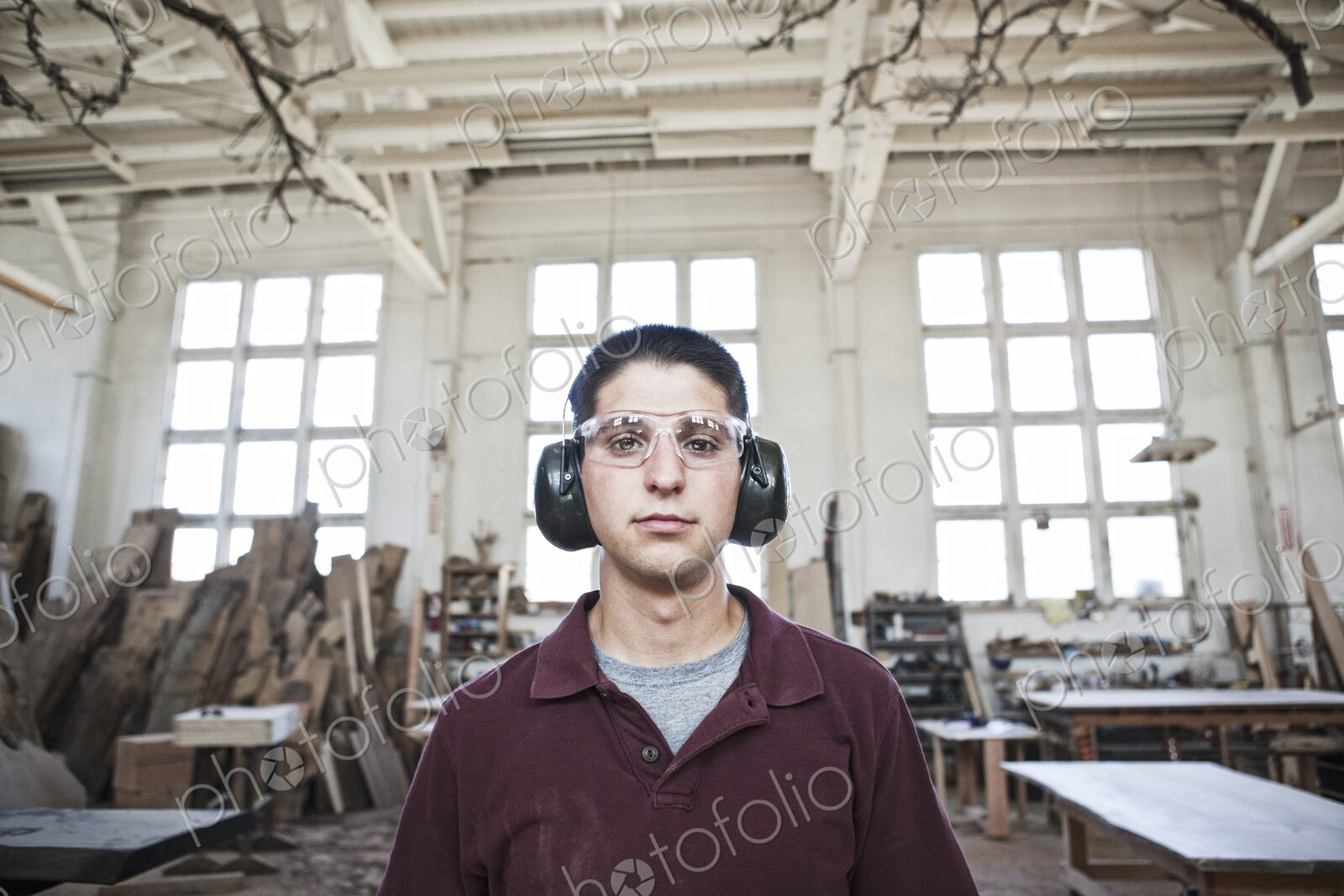 Caucasian man factory worker wearing hearing protection in a woodworking factory.