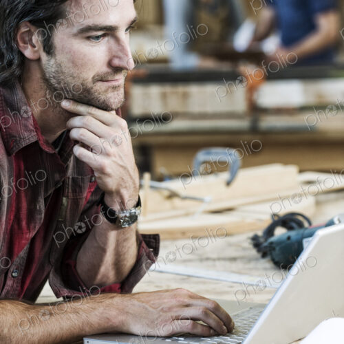 Caucasian man factory worker working on a lap top computer at a work station in a…