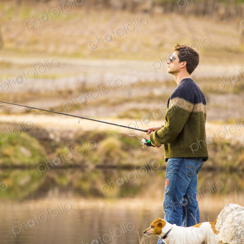 Caucasian man fishing with dog in remote lake