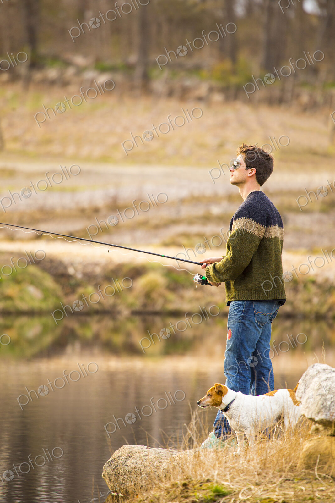 Caucasian man fishing with dog in remote lake