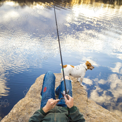 Caucasian man fishing with dog in remote lake