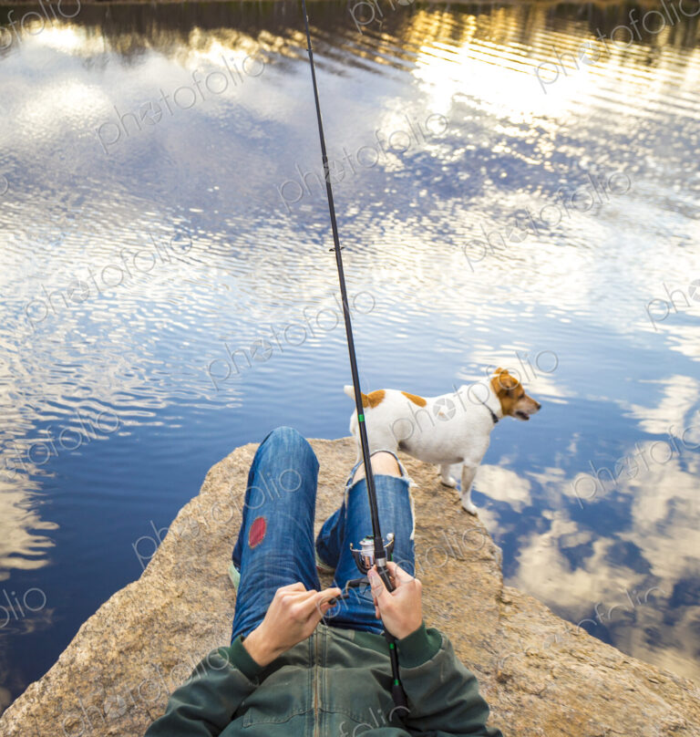 Caucasian man fishing with dog in remote lake