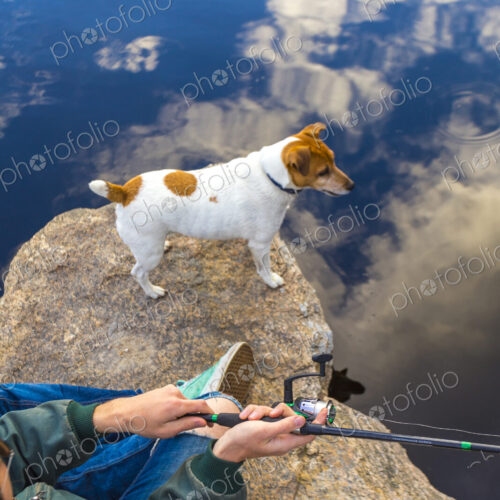 Caucasian man fishing with dog in remote lake