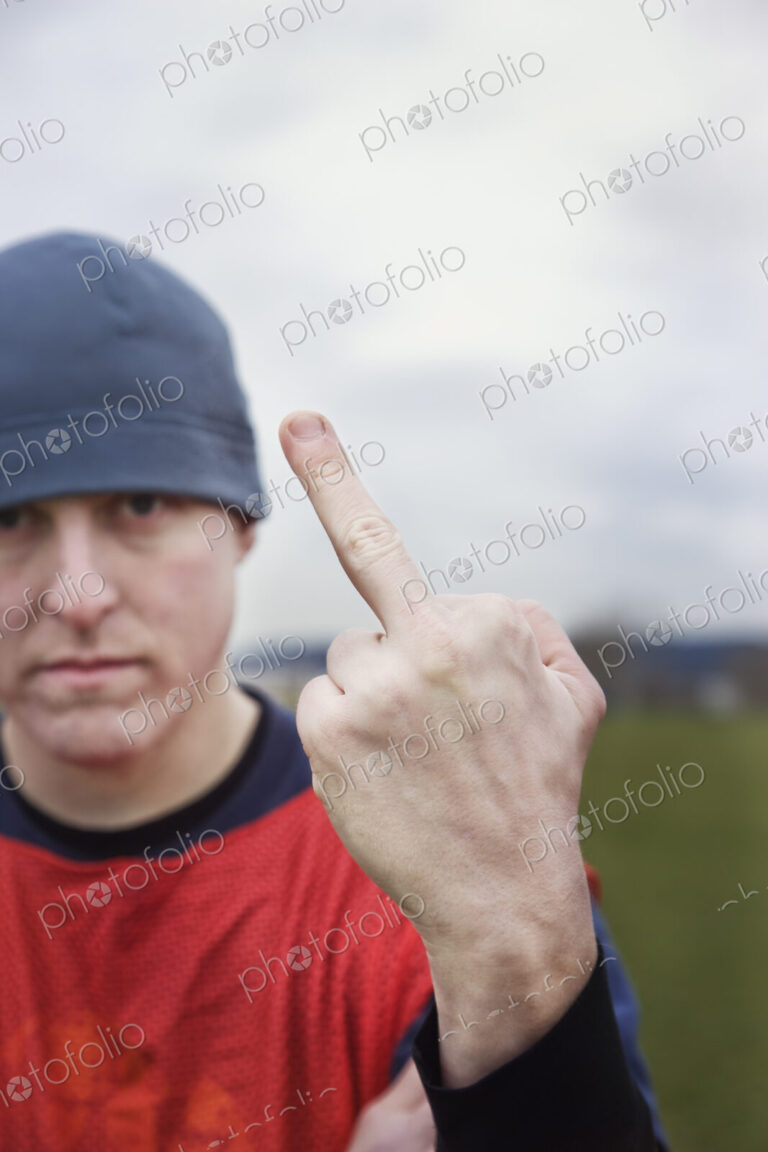 Caucasian man giving the viewer the finger as an obscene gesture.