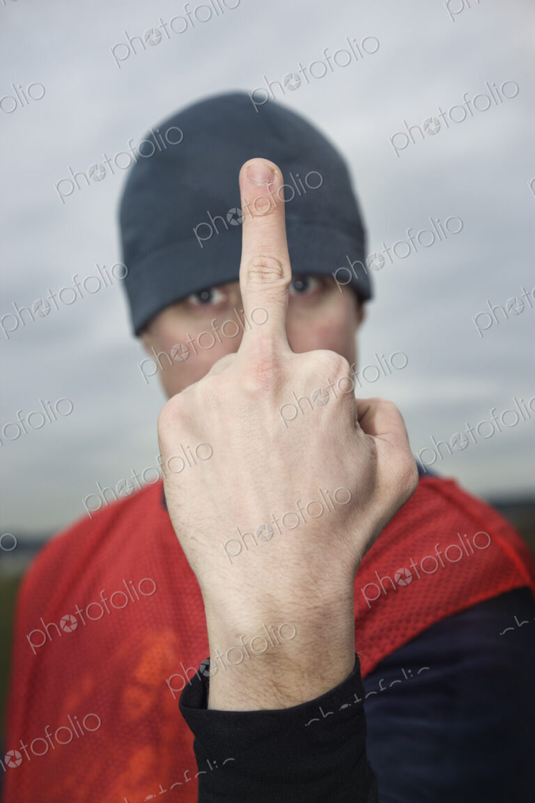 Caucasian man giving the viewer the finger as an obscene gesture.
