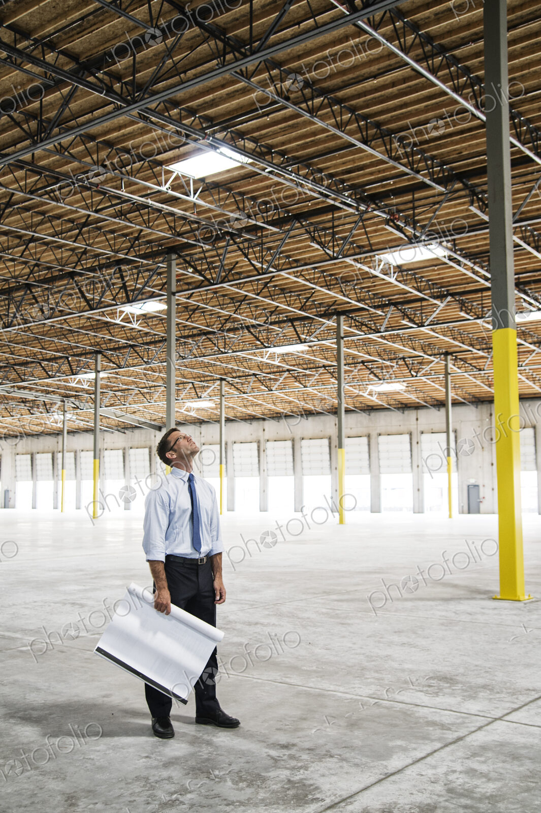 Caucasian man going over plans for new warehouse interior in front of loading dock doors.