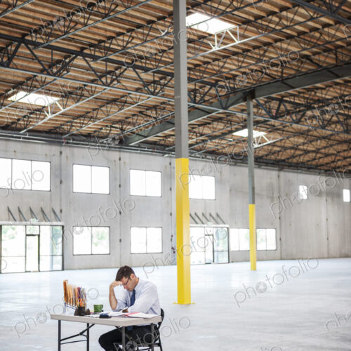 Caucasian man going over plans for new warehouse interior in front of loading dock doors.