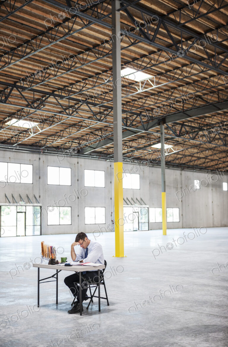 Caucasian man going over plans for new warehouse interior in front of loading dock doors.