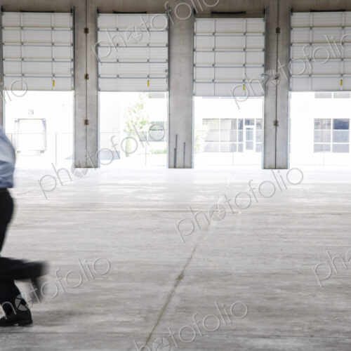 Caucasian man in dress shirt and slacks carrying brief case and plans running though… Caucasian man in dress shirt and slacks carrying brief case and plans running though…