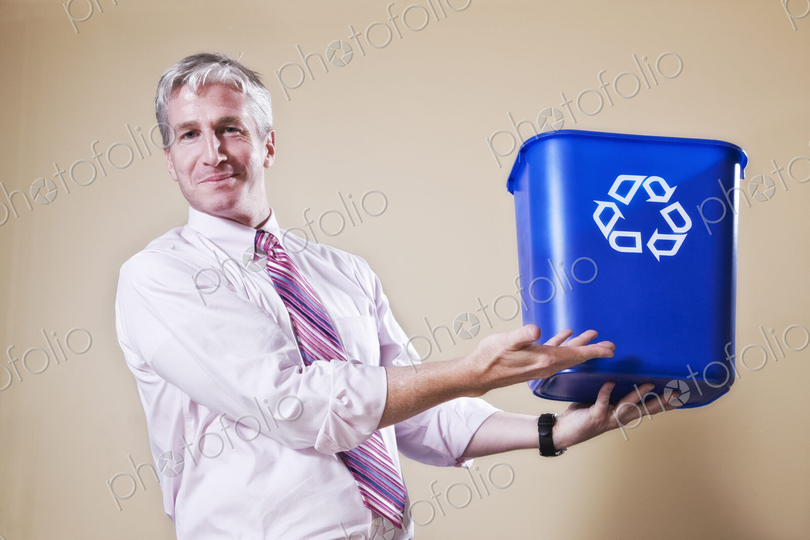 Caucasian man in shirt and tie holding a recycle waste bin.