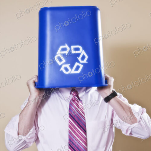 Caucasian man in shirt and tie holding a recycle waste bin.