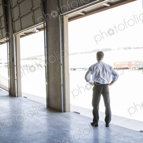 Caucasian man in shirt and tie standing in loading dock door of new empty warehouse… Caucasian man in shirt and tie standing in loading dock door of new empty warehouse…