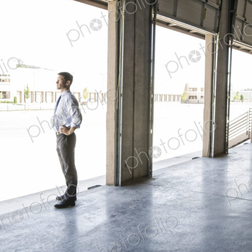 Caucasian man in shirt and tie standing in loading dock door of new empty warehouse… Caucasian man in shirt and tie standing in loading dock door of new empty warehouse…
