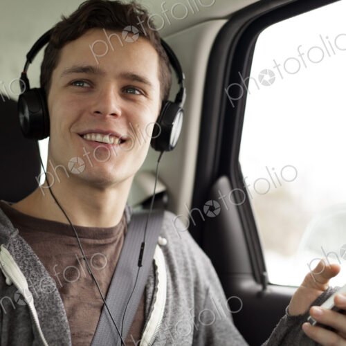 Caucasian man listening to mp3 player in car