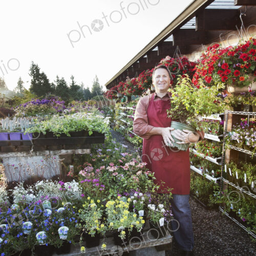 Caucasian man nursery owner standing with plants for sale at the nursery.