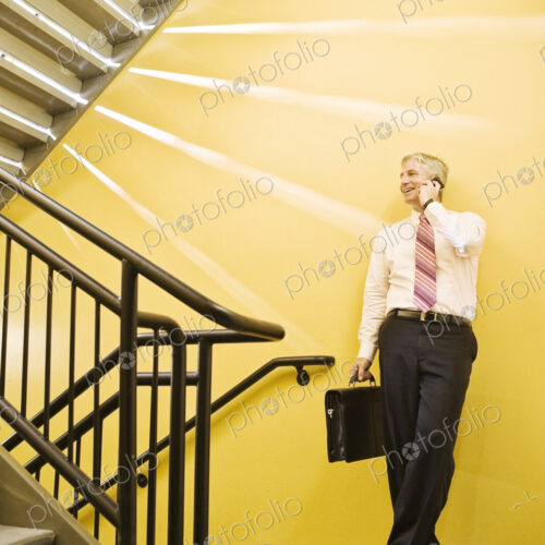 Caucasian man on the phone in an office stairwell.