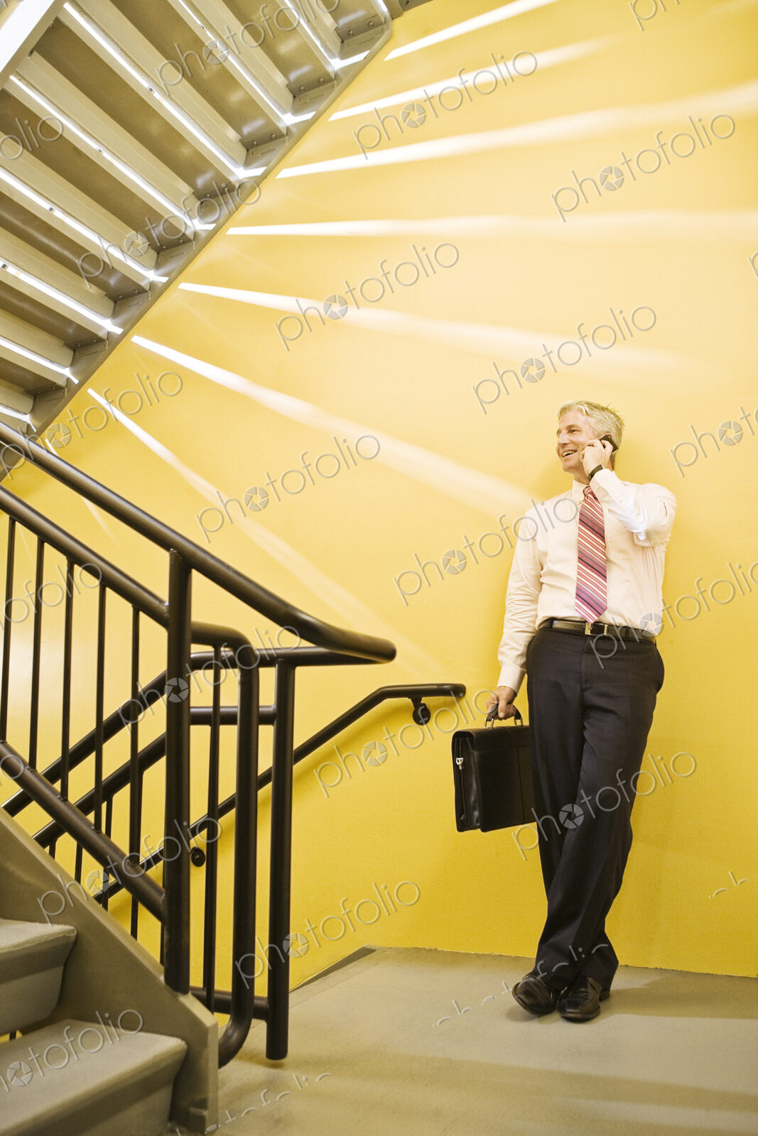 Caucasian man on the phone in an office stairwell.
