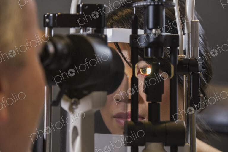 Caucasian man ophthalmologist using a slit lamp tonometer on a patient's eye.