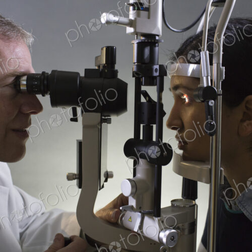 Caucasian man opthamologist using a slit lamp tanometer on a patient's eye. Caucasian man opthamologist using a slit lamp tanometer on a patient's eye.