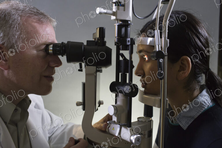 Caucasian man opthamologist using a slit lamp tanometer on a patient's eye.