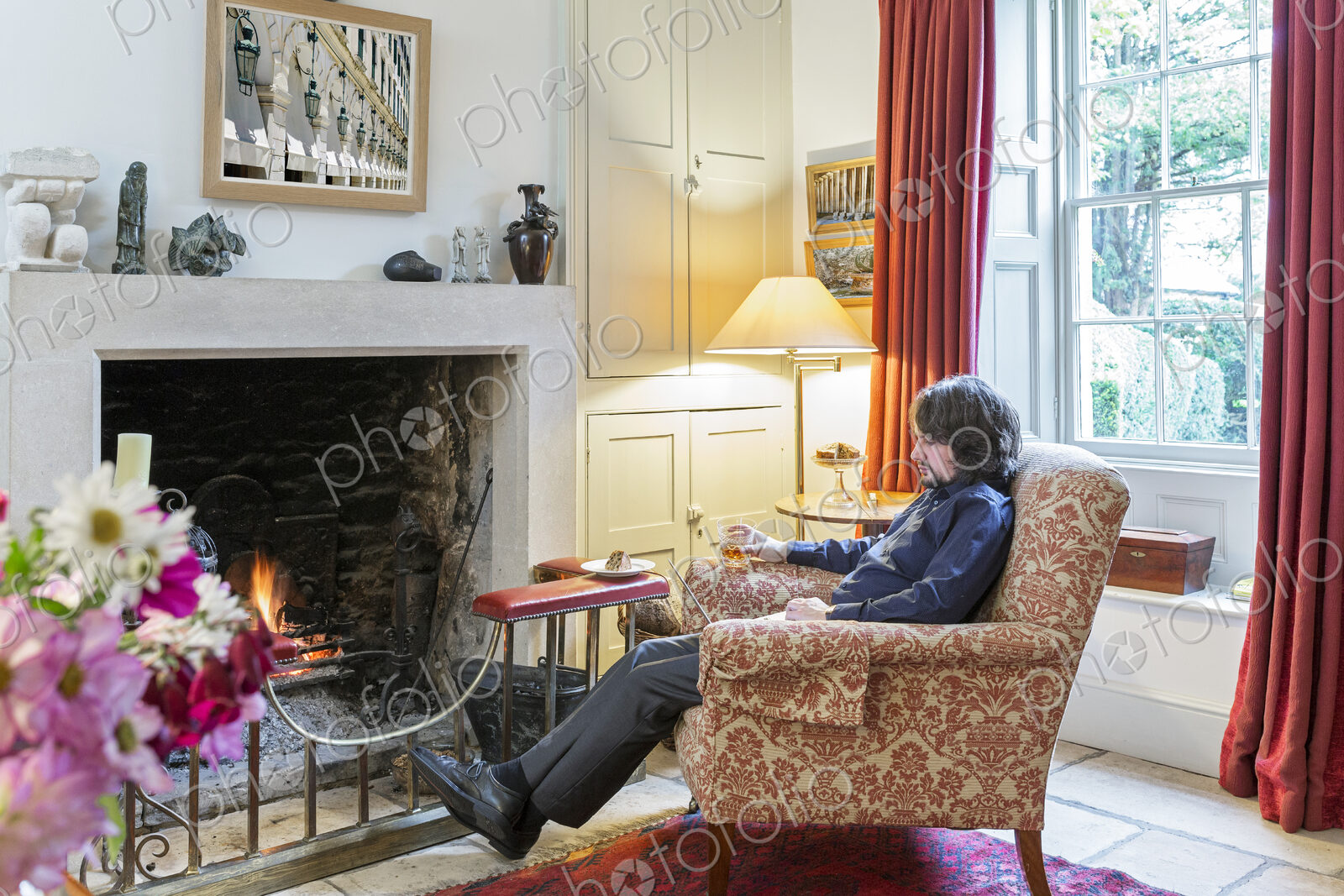 Caucasian man sitting in armchair near fireplace drinking cocktail