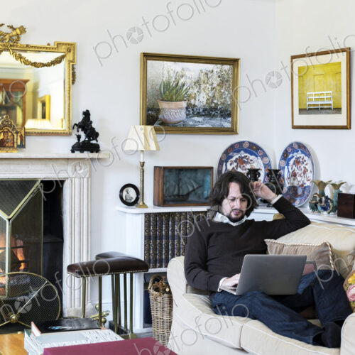 Caucasian man sitting on sofa using laptop Caucasian man sitting on sofa using laptop