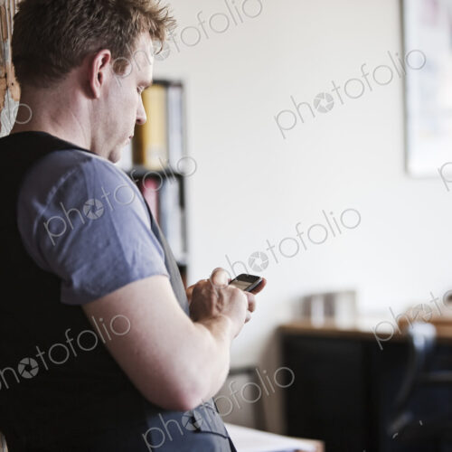 Caucasian man texting on his phone in his office. Caucasian man texting on his phone in his office.