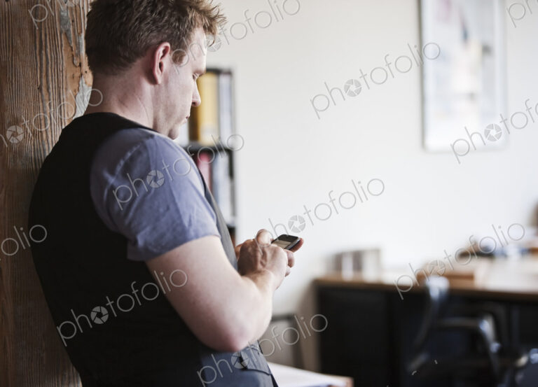 Caucasian man texting on his phone in his office.