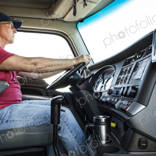 Caucasian man truck driver in the cab of his commercial truck.