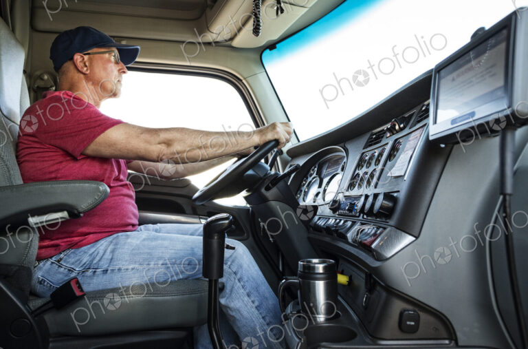 Caucasian man truck driver in the cab of his commercial truck.