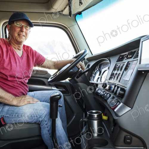 Caucasian man truck driver in the cab of his commercial truck.