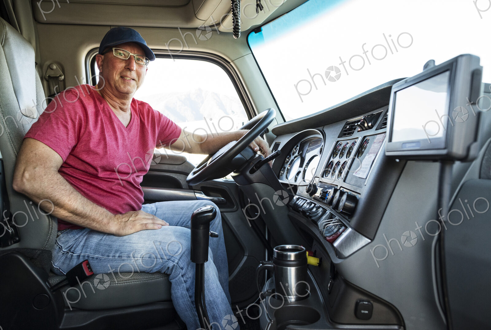 Caucasian man truck driver in the cab of his commercial truck.
