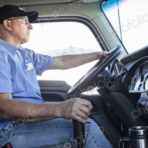 Caucasian man truck driver in the cab of his commercial truck.