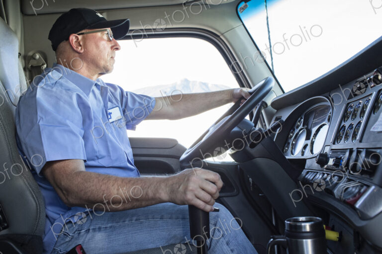 Caucasian man truck driver in the cab of his commercial truck.