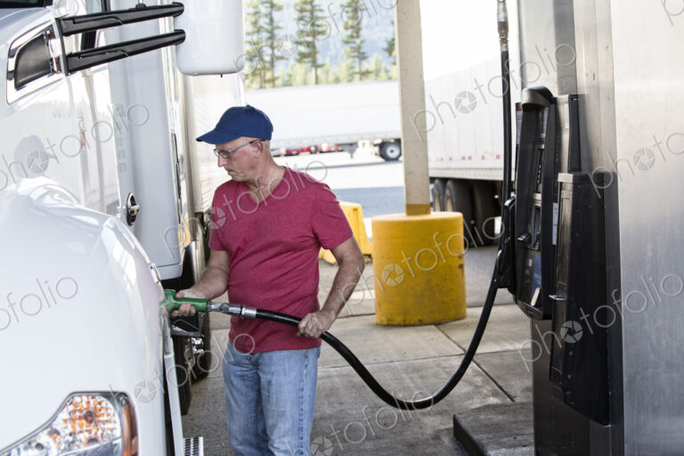 Caucasian man truck driver putting diesel fuel in his truck at a truck stop.