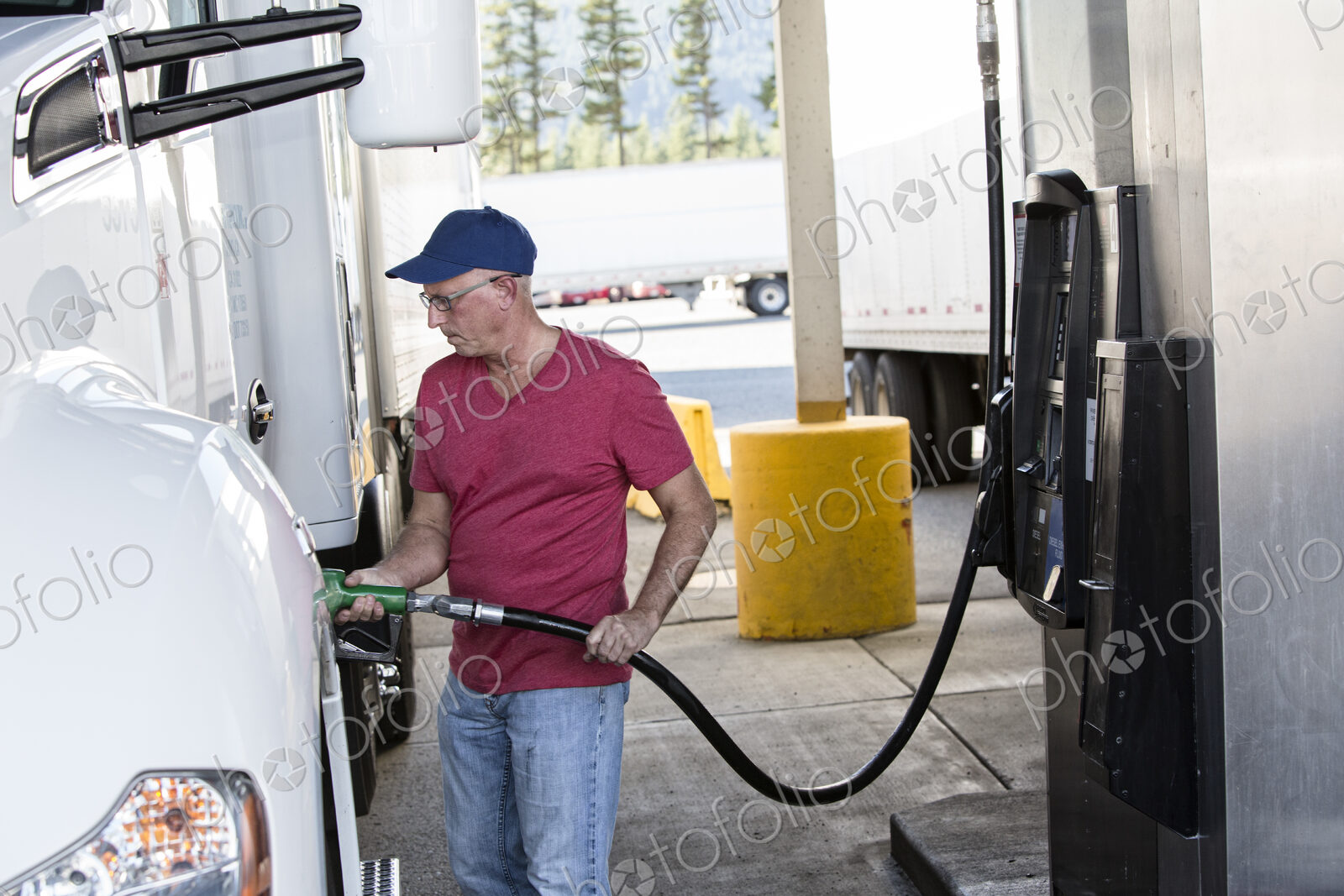 Caucasian man truck driver putting diesel fuel in his truck at a truck stop.