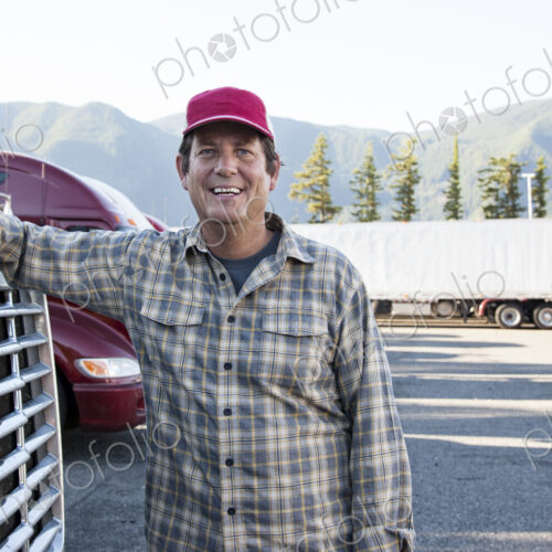 Caucasian man truck driver with his truck parked in a lot at a truck stop. Caucasian man truck driver with his truck parked in a lot at a truck stop.