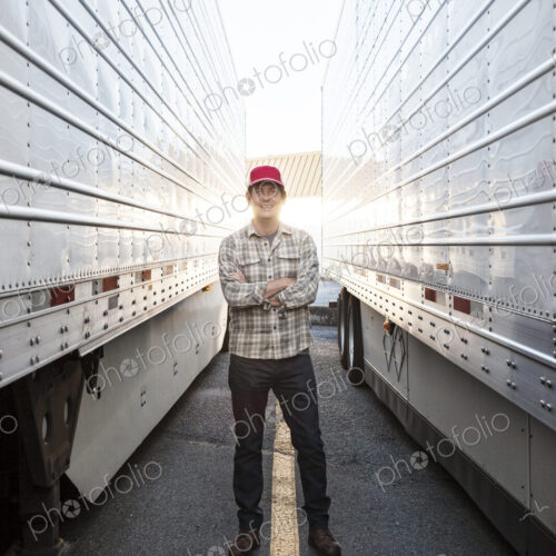 Caucasian man truck driver with his truck parked in a lot at a truck stop. Caucasian man truck driver with his truck parked in a lot at a truck stop.
