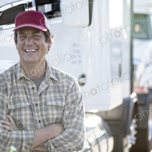 Caucasian man truck driver with his truck parked in a lot at a truck stop. Caucasian man truck driver with his truck parked in a lot at a truck stop.