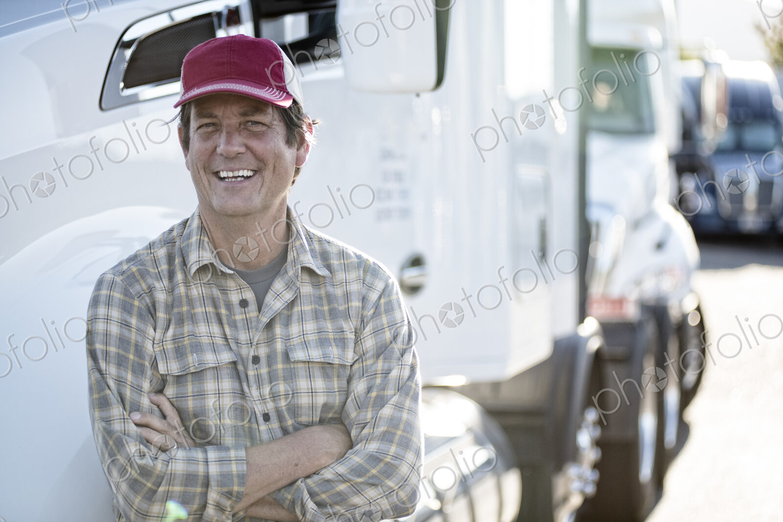Caucasian man truck driver with his truck parked in a lot at a truck stop.