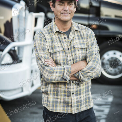 Caucasian man truck driver with his truck parked in a lot at a truck stop. Caucasian man truck driver with his truck parked in a lot at a truck stop.